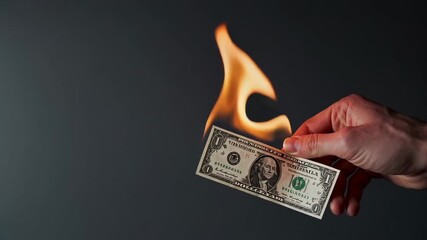 Confident businessperson burning crisp american dollar bill against neutral gray background, symbolizing financial volatility and economic uncertainty in global markets - Powered by Adobe