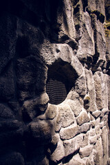 Historic textured stone structure in Bergpark Wilhelmshöhe featuring a round hole with mesh