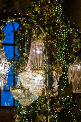 Elegant crystal chandeliers adorned with vibrant greenery and twinkling lights create a stunning ambiance in a beautifully decorated space with enchanting atmosphere