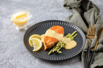 Steak salmon grill with asparagus sprouts, with hollandaise sauce in a plate on the table