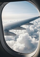 Aerial view through an airplane window of the wing, clouds, and sky. A travel, transport, or vacation related picture.