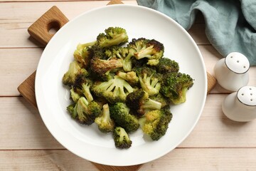 Tasty fried broccoli and shakers on light wooden table, flat lay