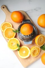 Squeezer with oranges and mint on white table, flat lay. Making fresh juice