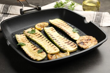 Delicious grilled courgette slices with garlic, lemon and parsley in pan on grey table, closeup