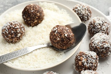 Making tasty chocolate candies with coconut flakes at grey table, closeup
