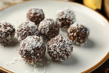 Tasty chocolate candies with nuts and coconut flakes on table, closeup