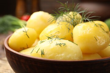 Tasty young boiled potatoes with dill and oil in bowl on table, closeup