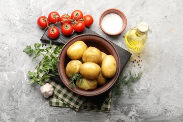 Tasty young boiled potatoes with dill, oil in bowl, salt and products on grey textured table, flat lay