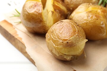 Tasty baked potatoes served on white wooden table, closeup