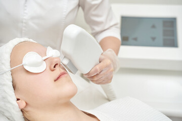 Female receiving laser skin treatment in spa clinic for facial rejuvenation.