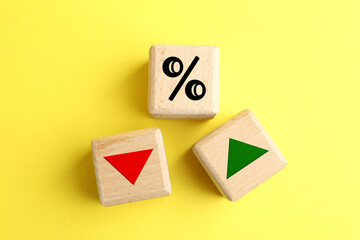 Wooden cubes with percent sign, up and down arrows on yellow background, top view