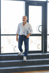 Fototapeta premium Handsome and successful senior business man walking stairs in modern office