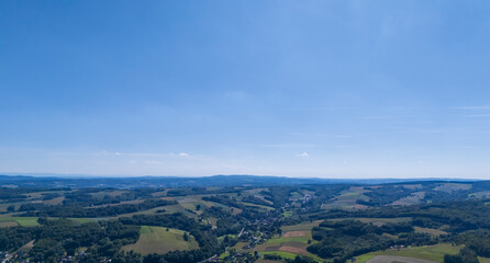 Fototapeta premium A panoramic view of rolling green hills under a clear blue sky, capturing the serene beauty of the countryside landscape. Ideal for nature and travel themes.
