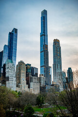 Obraz premium Skyscrapers near Central Park. Visitors admire New York's skyline near Central Park as evening light highlights the tall buildings and greenery.