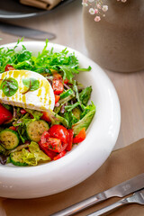 Vibrant garden salad. Colorful salad featuring fresh lettuce, tomatoes, cucumbers, and herbs served in a white bowl.