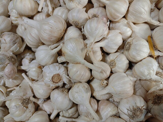 A close-up shot of fresh organic garlic bulbs, a healthy and raw spice, displayed at a market