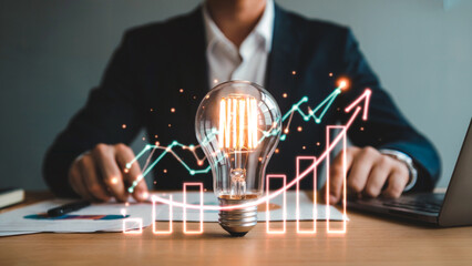 Clear glass bulb reflects orange light and a diagram, showcasing business data and idea generation for presentation or stock photo.