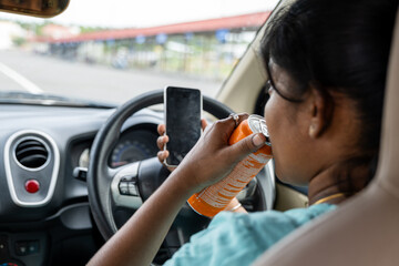 Driver consuming beverage while using smartphone