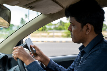 Man using smartphone while driving on a sunny day