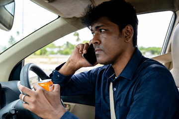 Man talking on phone while driving car and holding drink