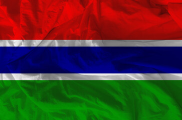 Stylized image of the Gambian flag with a crumpled paper texture and halftone effect. Concept of statehood.