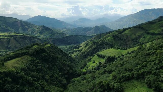 Drone shot flying through the mountains covered with tree or surrounded by clouds .