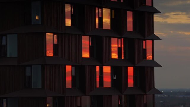 Aerial drone view of Copenhagen's Domus Vista skyscraper with fiery sunset reflections in its windows