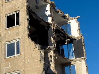 Partially collapsed building with exposed interiors against clear blue sky