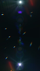 Dark abstract background with colorful light streaks, lens flares and bokeh effects. Mysterious atmosphere with blue, purple and rainbow light elements.