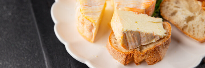 Washed rind cheese soft cheese with orange rind munster french cheese tasty snack fresh delicious gourmet food background on the table rustic top view copy space