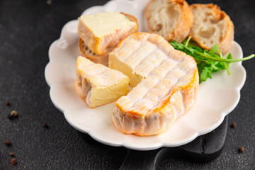 Washed rind cheese soft cheese with orange rind munster french cheese tasty snack fresh delicious gourmet food background on the table rustic top view copy space