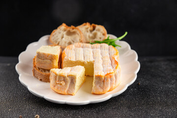 Washed rind cheese soft cheese with orange rind munster french cheese tasty snack fresh delicious gourmet food background on the table rustic top view copy space