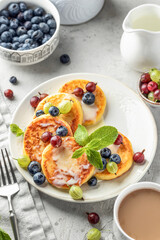 Cottage cheese pancakes with berries, mint leaves and condensed milk. Homemade dessert syrniki for healthy breakfast