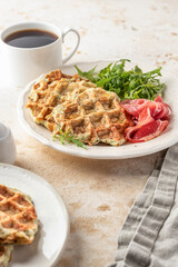 Zucchini waffles served with arugula salad and prosciutto. Healthy vegeterian food