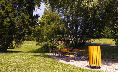 Sitting in the park. Place in the park for sitting and picnic. Iron benches and table. Trash can. Park with a place to rest. Sunny summer day. Park in the Czech Republic. Staying in the fresh air