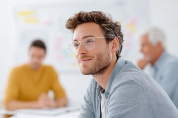 Man wearing glasses is sitting at a table with two other people