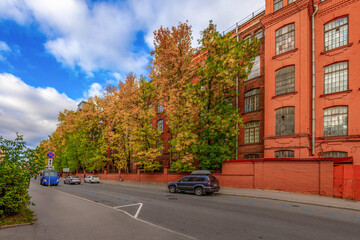 Perspective view of red brick Neva Thread Manufactory building with autumn maple trees under blue...