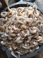 A large bowl filled with many raw, peeled shrimp, ready to be cooked.