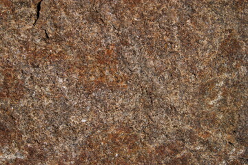 Close-up of rough granite rock surface with natural texture and earthy tones, ideal for backgrounds, geology themes, and construction materials.