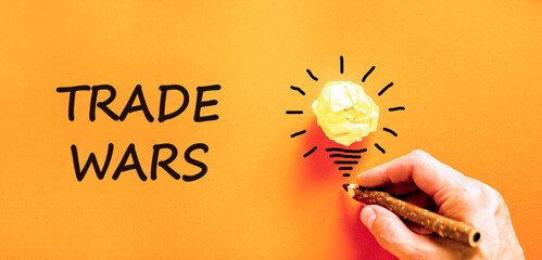 Trade wars symbol. Concept word Trade wars on beautiful orange paper. Businessman's hand. Light...