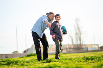 Grandfather pointing and smiling while boy holds ball in field