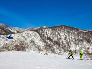 A ski instructor giving a lesson to a student at the slope on a sunny winter day (Togari Onsen, Nagano, Japan)