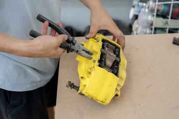 A skilled car mechanic works on a brake caliper in a well-equipped workshop. Using pliers, the technician carefully performs repairs to maintain vehicle functionality.