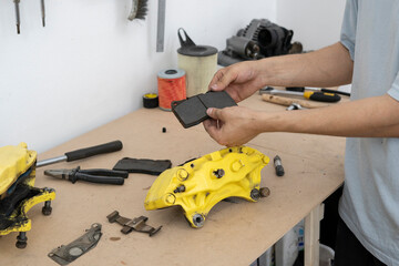 A skilled car mechanic works on a brake caliper in a well-equipped workshop. Using pliers, the technician carefully performs repairs to maintain vehicle functionality.