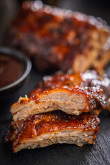 Pork BBQ glazed ribs on black table.