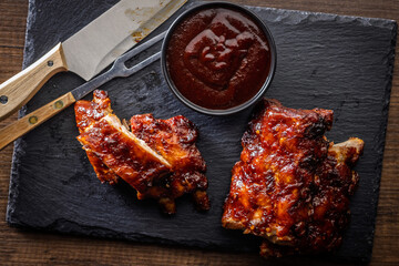 Pork BBQ glazed ribs and sauce on cutting board. Top view.