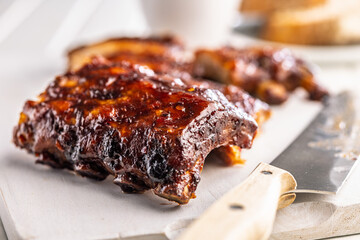Pork BBQ glazed ribs on white cutting board.