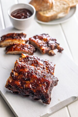 Pork BBQ glazed ribs on white cutting board.