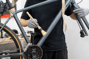 A mechanic is focused on cleaning the gears and chain of a bicycle using a specialized brush. This task is essential for maintaining the bike's efficiency and prolonging its lifespan.