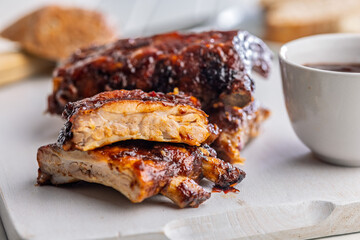 Pork BBQ glazed ribs on white cutting board.